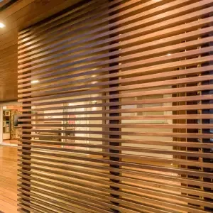 Brise de alumínio com lâminas horizontais em tom bronze metálico, instalado como painel decorativo em ambiente interno com forro de madeira